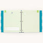 An open three-ring binder planner or agenda with pale green lined pages, teal polka-dot side panels, and small decorative printed details on the pages, shown against a plain light background.