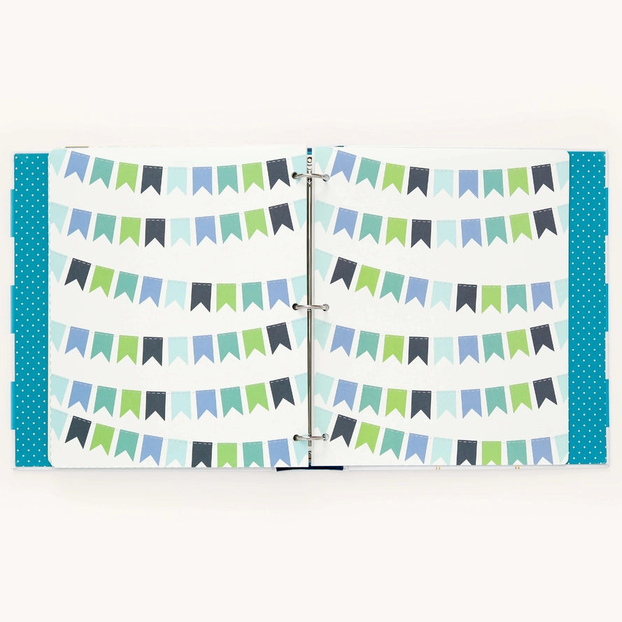 A three-ring binder notebook or planner shown open, featuring a pattern of horizontal bunting banner garlands in shades of green, blue, and gray on a white background, with teal polka-dot side covers.