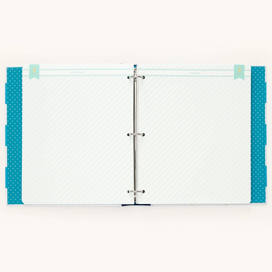 A two-ring binder planner or agenda with white patterned pages and bright teal blue dotted side borders, shown against a plain white background.