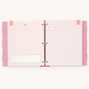 A light pink binder with three rings, featuring decorative pink side tabs, a blank white text box on the left page, and small circular inserts, shown against a plain off-white background.