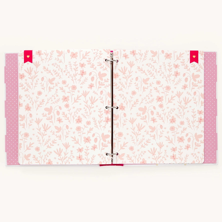 A three-ring binder notebook or planner cover featuring a delicate pink floral and heart pattern on a white background, with pink polka-dotted side tabs and red ribbon ties.