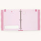 An open pink ring-bound journal or planner binder with lined pages, decorative pink polka-dot side tabs, and small printed birthday-themed illustrations on a plain light background.
