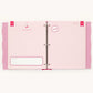 An open pink ring binder planner or keepsake album with lined pages, decorative pink side tabs, and printed heart and circle labels on a light neutral background.