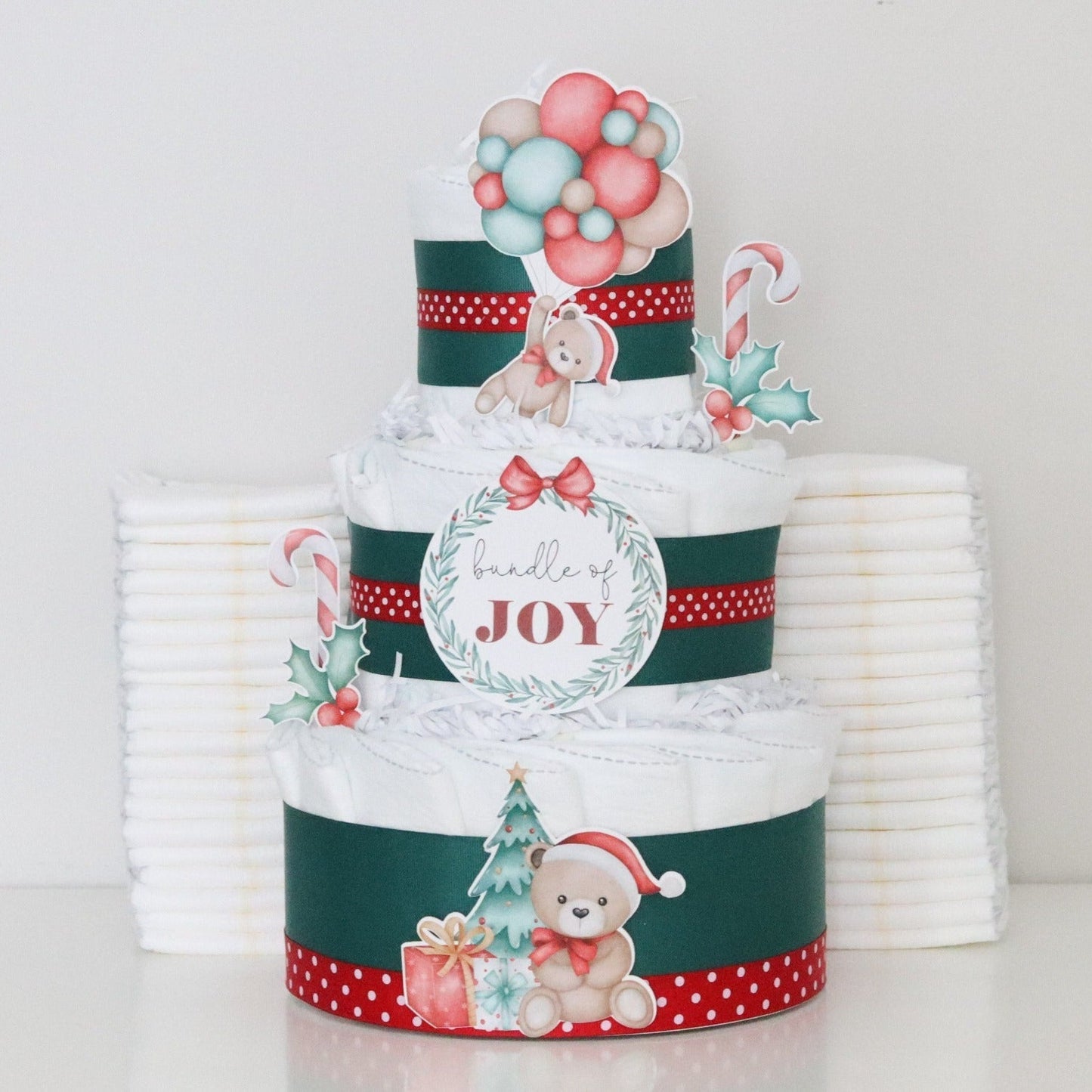 three-tiered diaper cake with Christmas-themed decorations on a white background